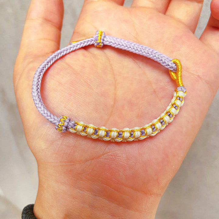 Bracciale intrecciato con nodo di collegamento in fili d'oro tibetani con pietre Buddha Stones e fiori di pesco colorati