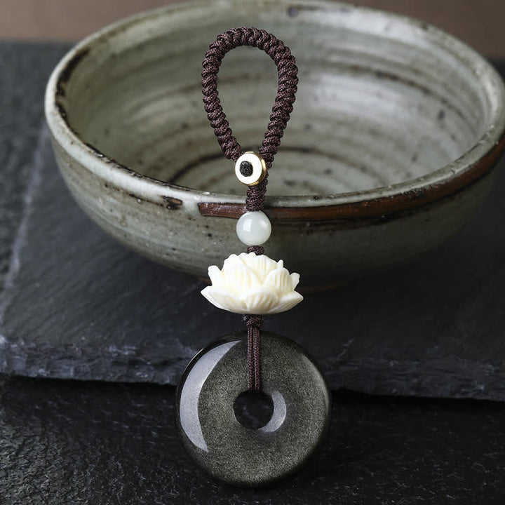 Buddha Stones Portachiavi di protezione con fibbia a loto e simbolo della pace in ossidiana arcobaleno. - Lotus - Portachiavi con fibbia a forma di pace in ossidiana con lucentezza dorata - Ossidiana arcobaleno (cambia colore a seconda della luce) - image 0