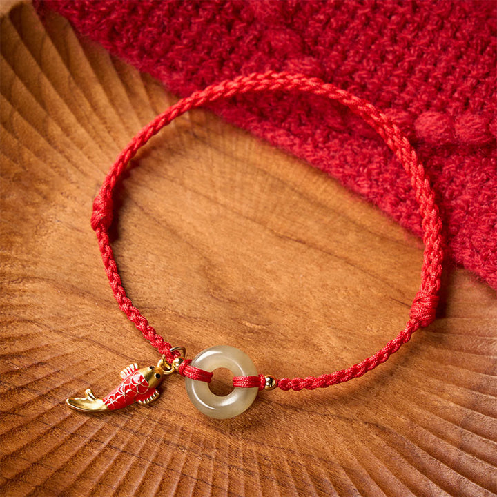 Buddha Stones Braccialetto protettivo con fibbia a forma di pesce koi, cordino rosso e giada, con ciondolo della pace. - Giada naturale (il colore può variare) - 16-18 cm - image 0