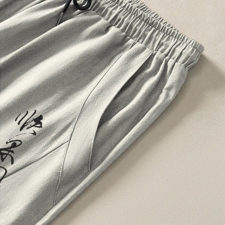 Buddha Stones Pantaloni da uomo affusolati con coulisse e tasche, in puro cotone, con motivo a fiori di pruno e scritta calligrafica. - image 4