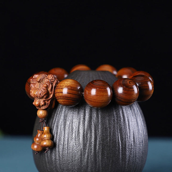 Braccialetto di protezione intagliato a forma di drago con piccole foglie di sandalo rosso, in palissandro e sandalo verde Buddha Stones